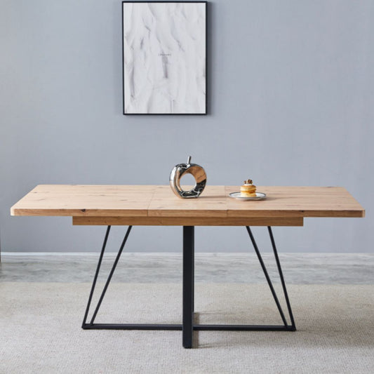 Wooden dining table with black metal legs in a room with a grey wall and abstract art.