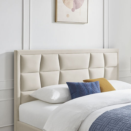 Beige upholstered headboard with pillows on a bed against a white wall.