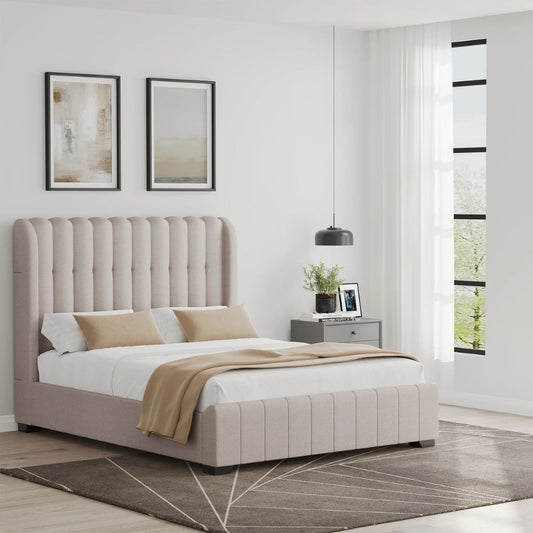 Beige upholstered bed in a modern bedroom with white walls and large windows.