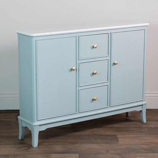 Sage green sideboard with gold handles on a wooden floor against a gray wall.