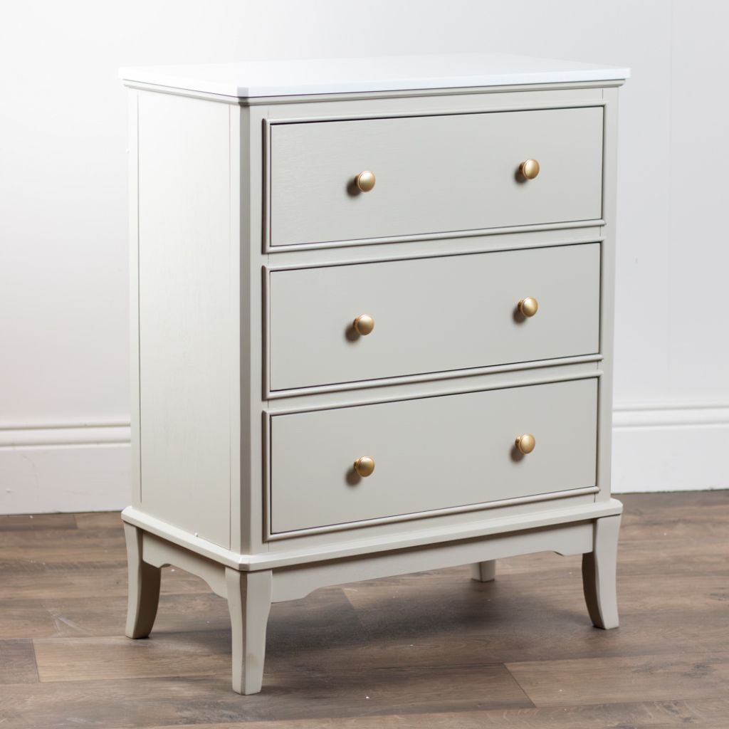 Stone dresser with gold knobs on a wooden floor against a white wall