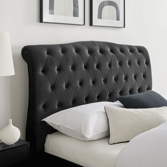 Black tufted headboard with pillows on a bed in a bedroom setting.