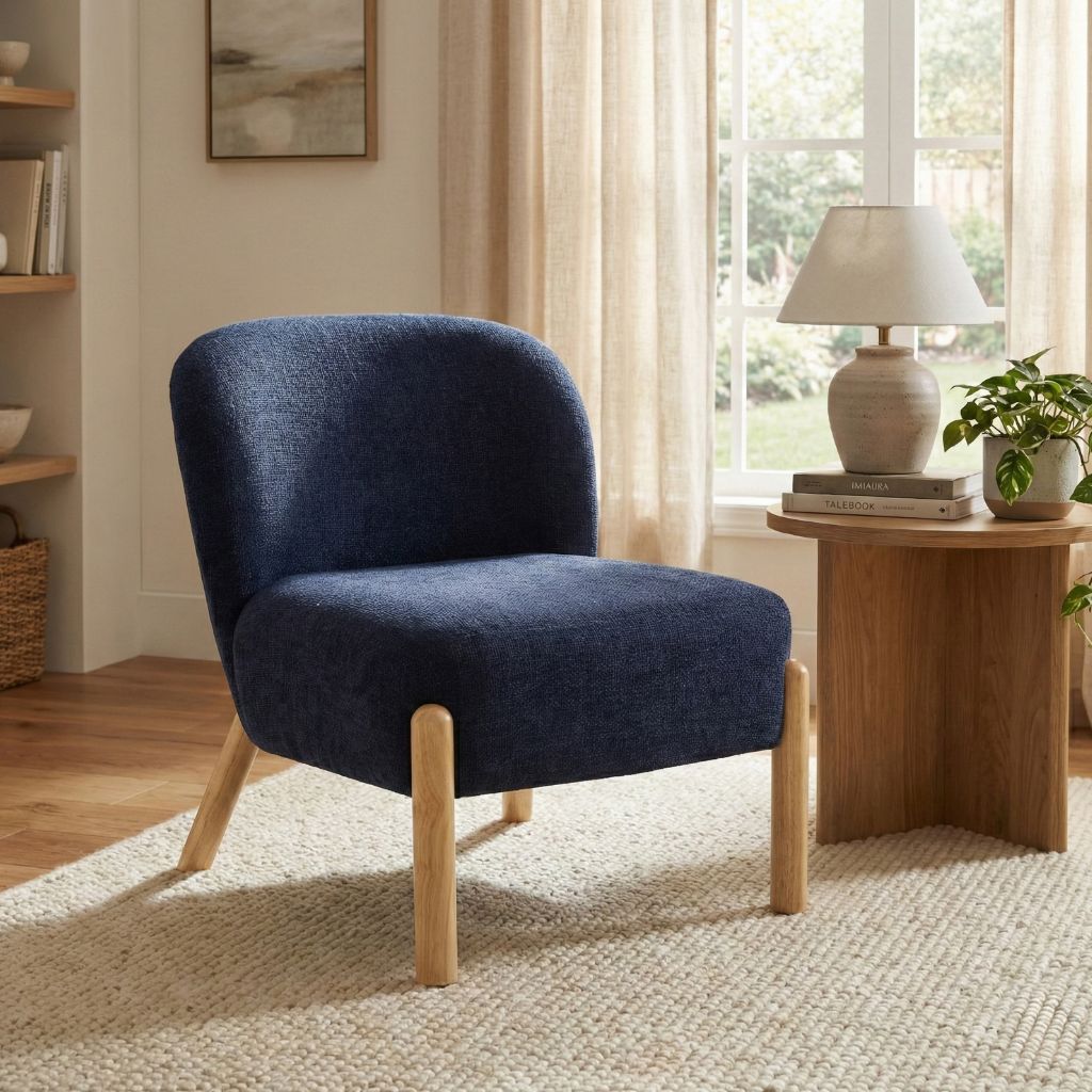 Blue armchair in a living room with wooden side table and window in background
