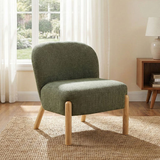 Green upholstered chair with wooden legs in a room with a window and lamp.