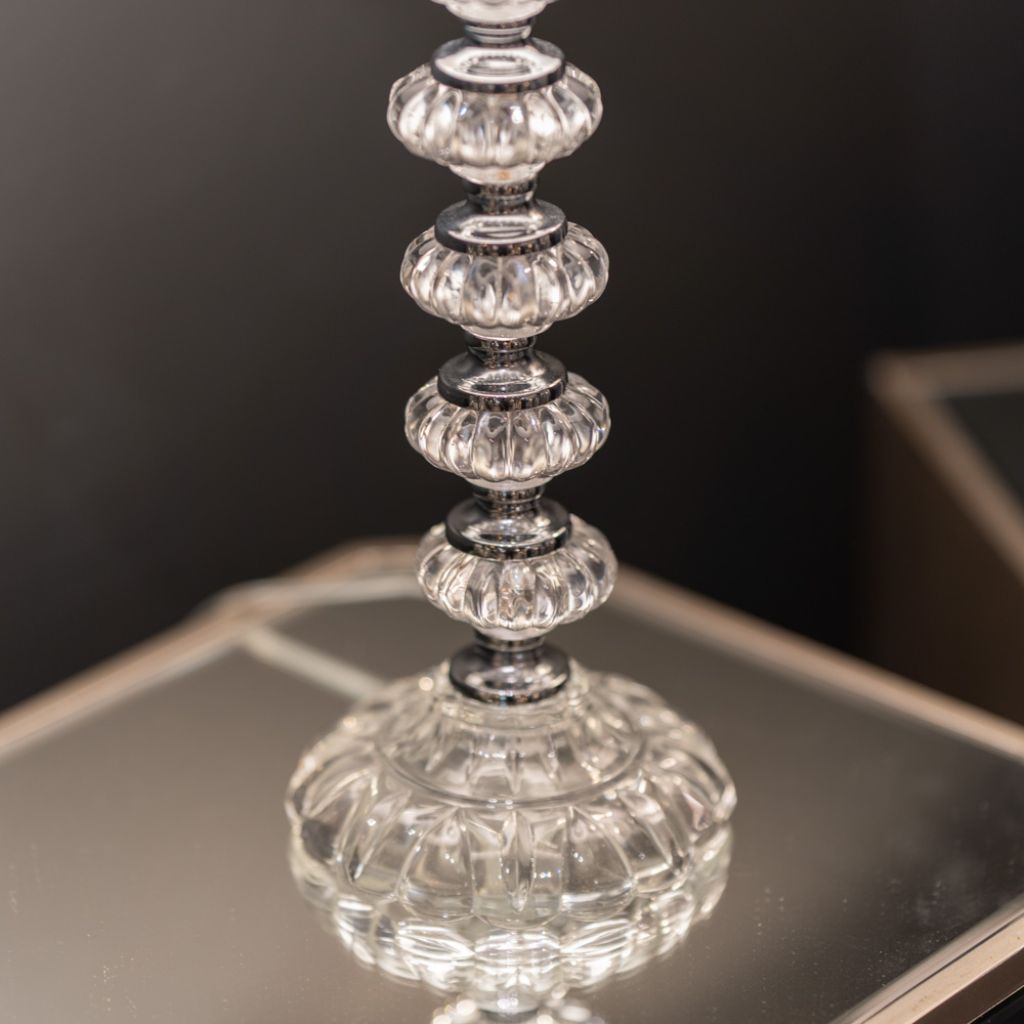 Close-up of a crystal candle holder on a reflective surface with a dark background