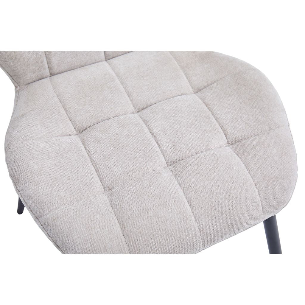 Close-up of a beige upholstered chair with quilted pattern on a white background