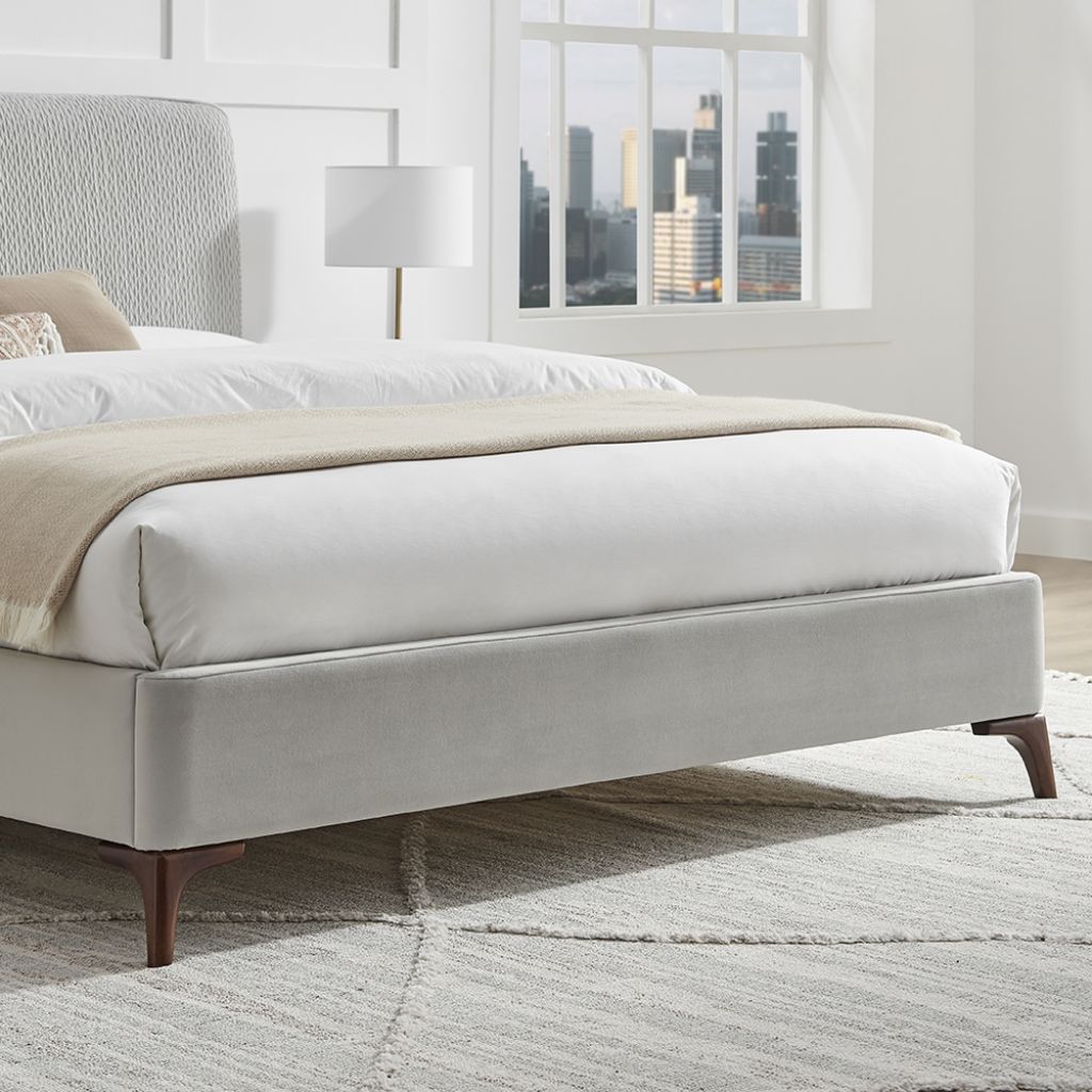 Modern bed with white bedding and beige blanket in a room with large windows and cityscape view.