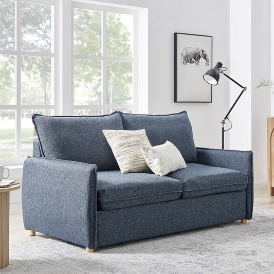 Blue sofa with cushions in a room with large windows and a lamp.