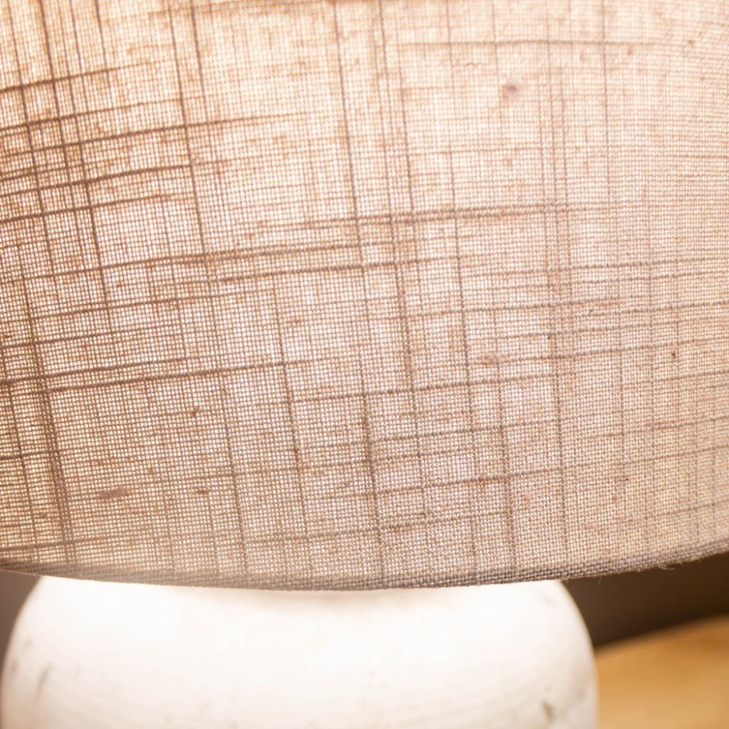 Close-up of a textured beige lampshade on a white base.