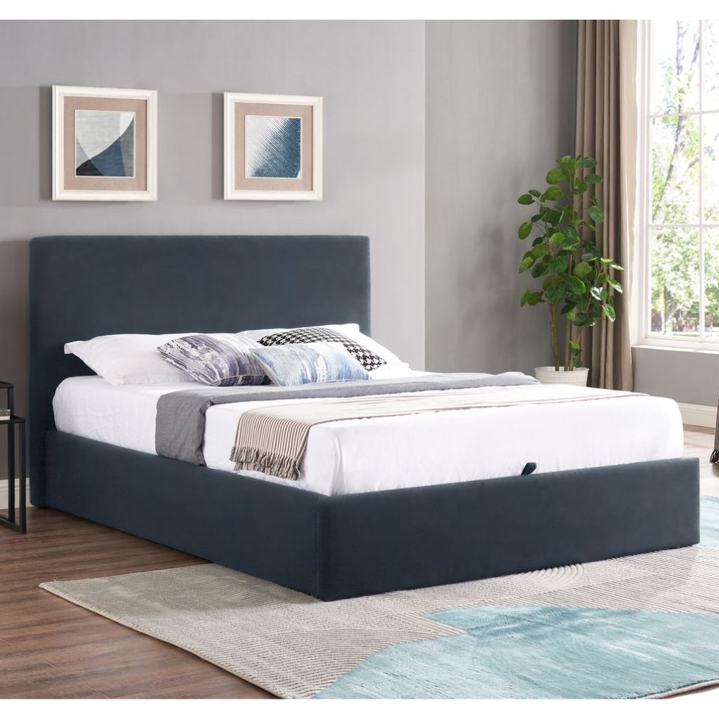 Navyupholstered bed in a room with gray walls, a plant, and a rug.