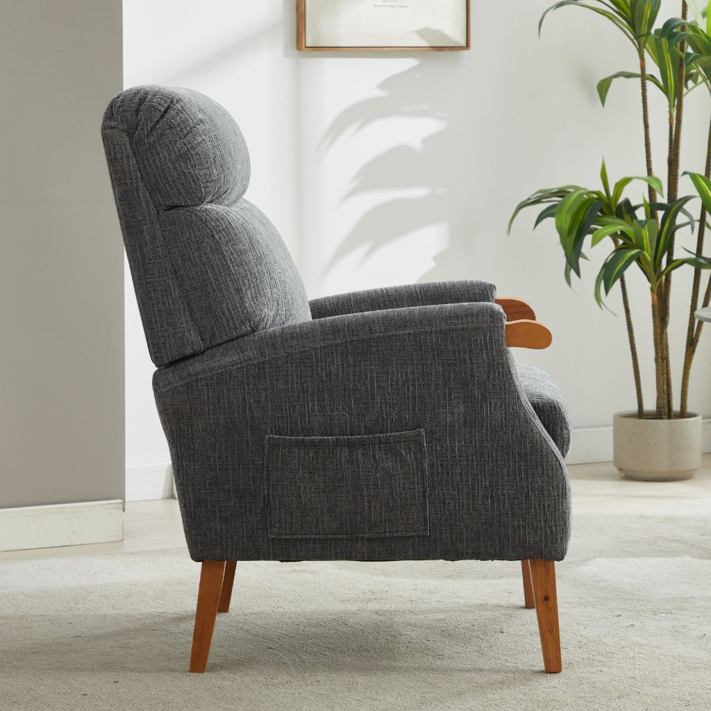 Gray armchair with wooden legs in a room with a plant and framed picture on the wall.