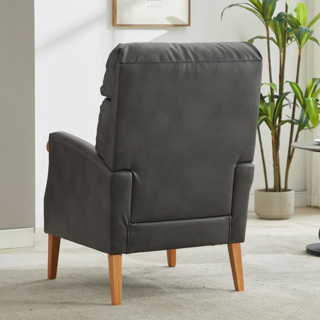 Gray armchair with wooden legs in a room with a plant and framed picture on the wall.