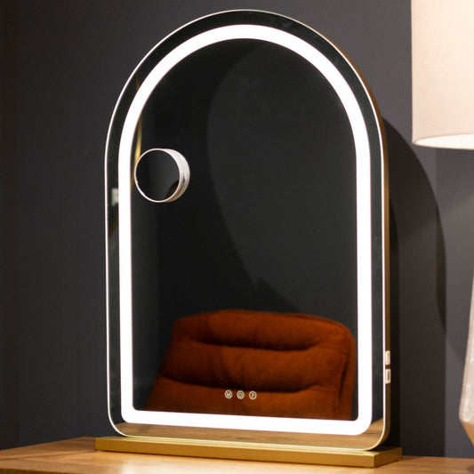 Decorative mirror with LED lighting on a wooden surface against a dark wall.