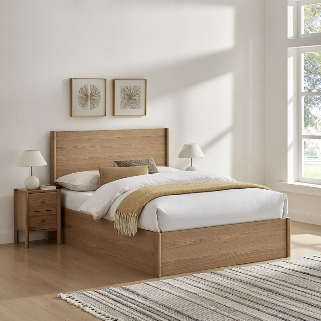 Wooden bed with white bedding and a striped rug in a bright bedroom.