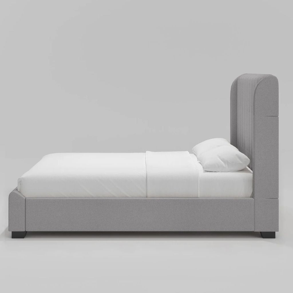 Grey upholstered bed with white bedding on a light gray background