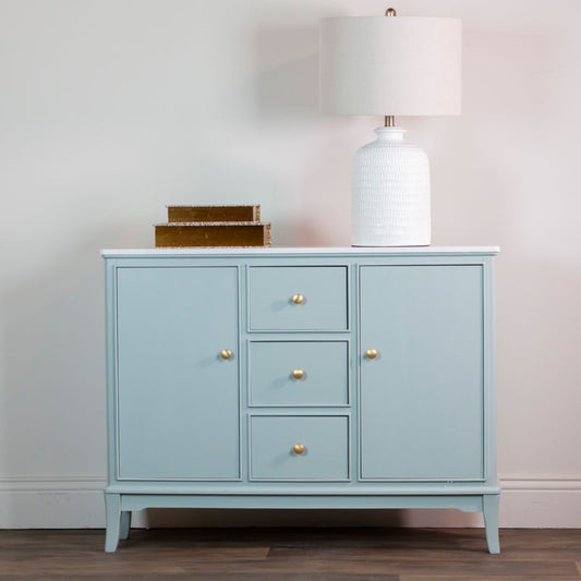Sage green cabinet with gold knobs against a neutral wall