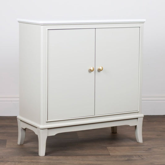 Stone cabinet with gold handles on a wooden floor against a white wall