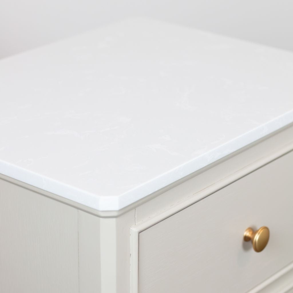 Close-up of a stone cabinet with a white countertop and gold handle.