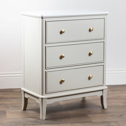 Stone dresser with gold knobs on a wooden floor against a white wall