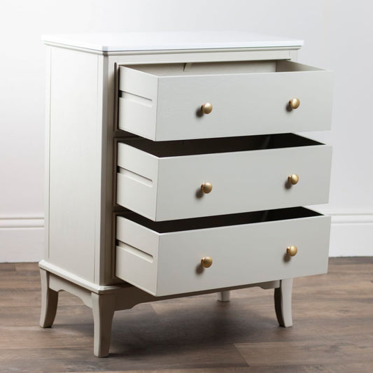 Stone dresser with gold knobs on a wooden floor against a white wall