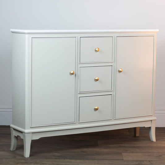 Stone sideboard with gold handles on a wooden floor against a white wall.
