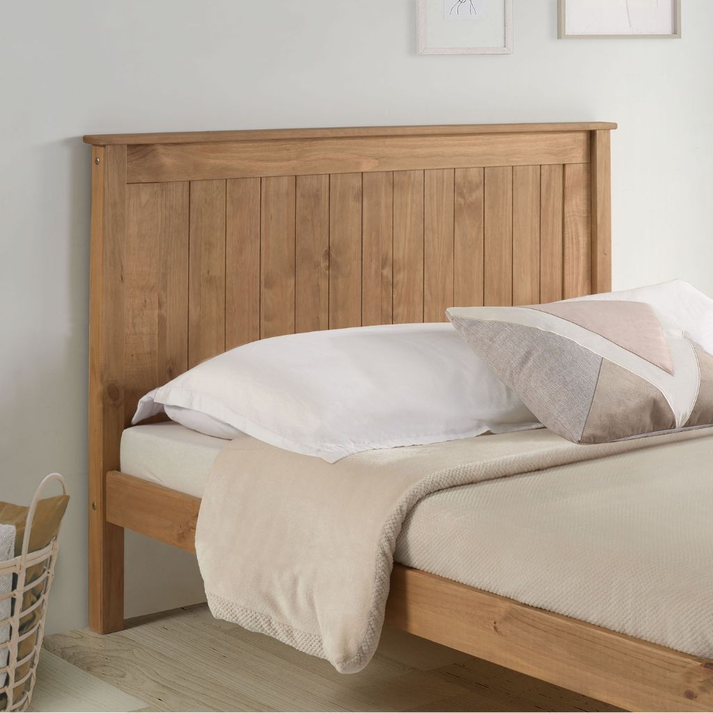 Wooden bed with white bedding and a basket on a light wooden floor.